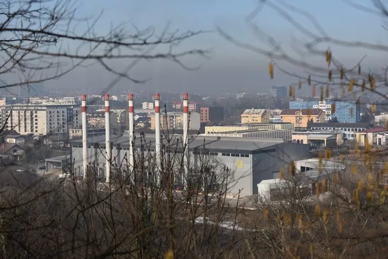 Pogled na industrijsku zonu i grad prekriven smogom.