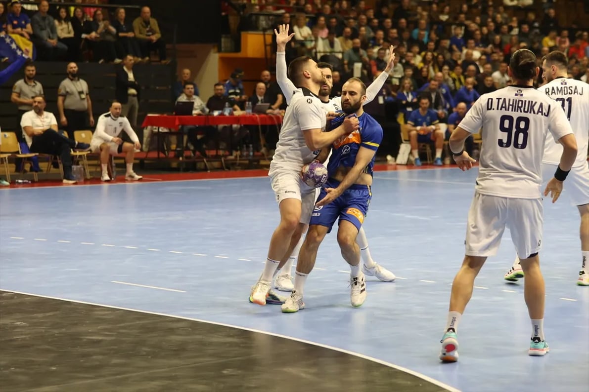 Dva rukometna igrača u borbi za loptu na terenu.