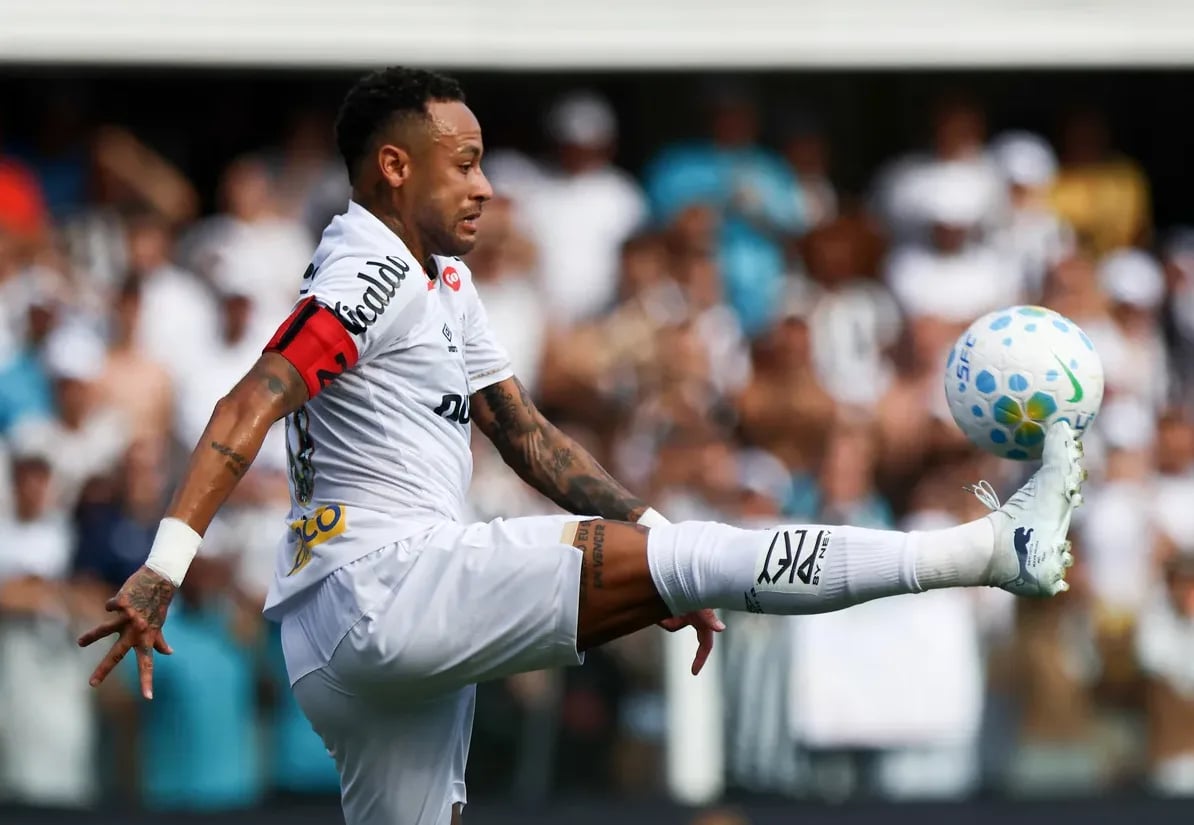 Fudbaler Neymar Jr. u bijelom dresu izvodi akciju sa fudbalskom loptom.