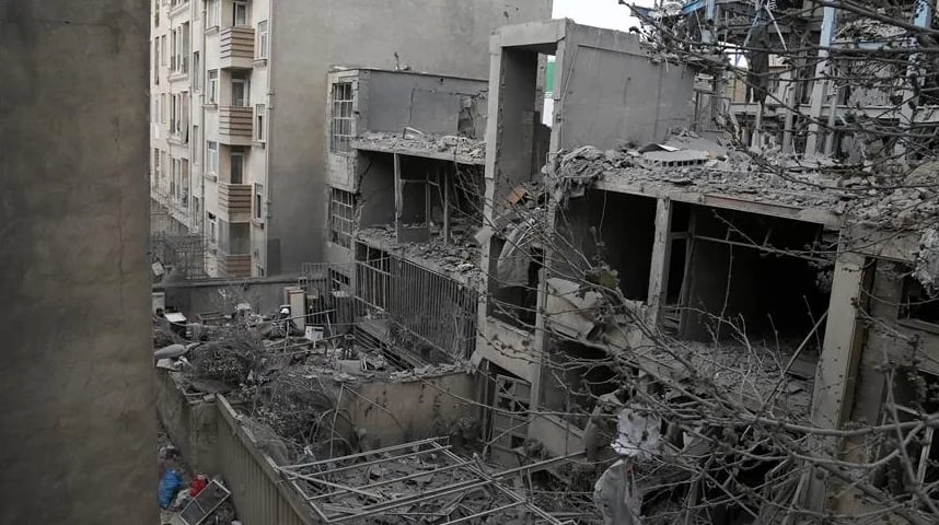 Prizor uništenih zgrada nakon sukoba, sa oštećenim fasadama, polupanim prozorima i krhotinama construction materijala na sve strane.