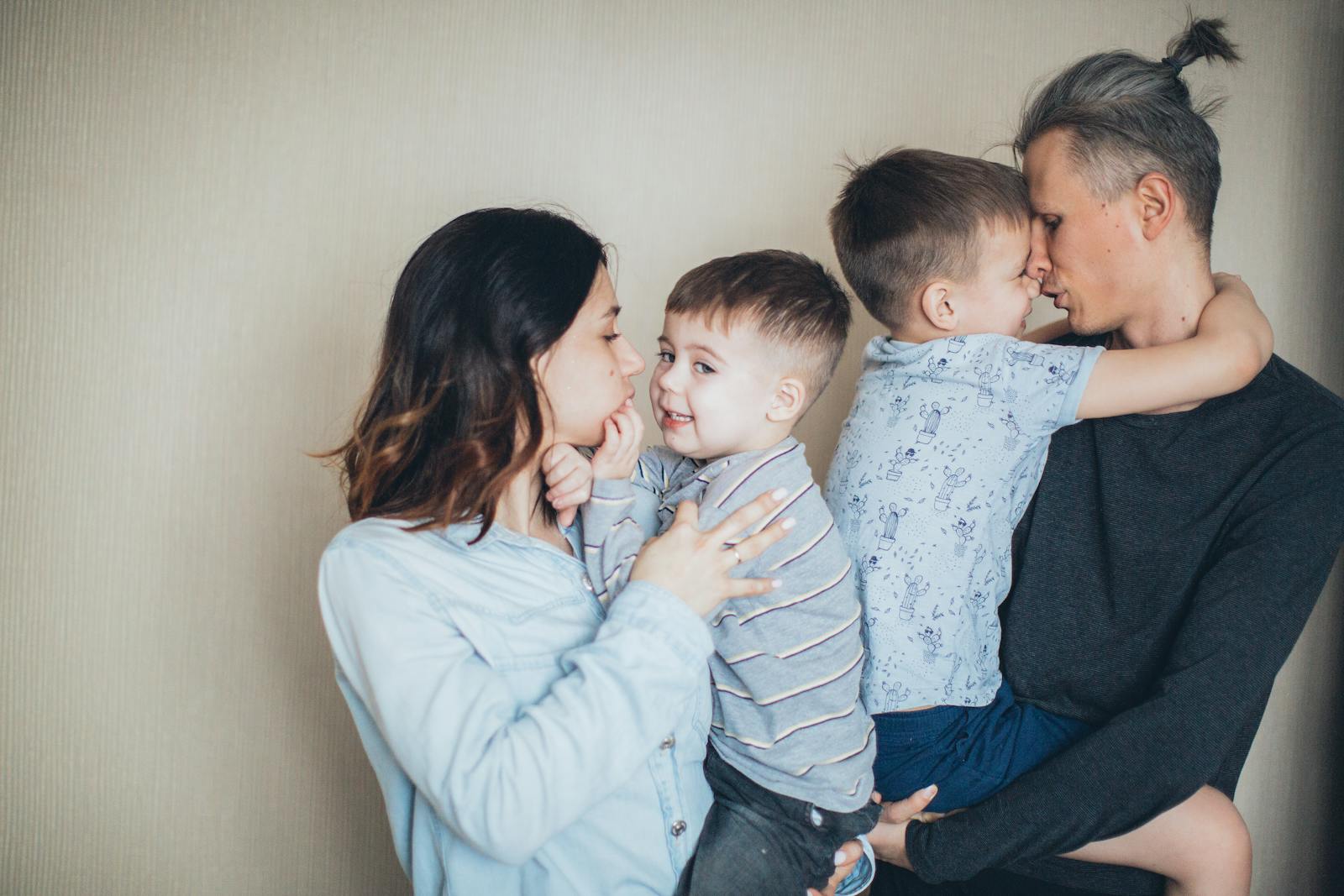 A loving family of four sharing moments of affection indoors.