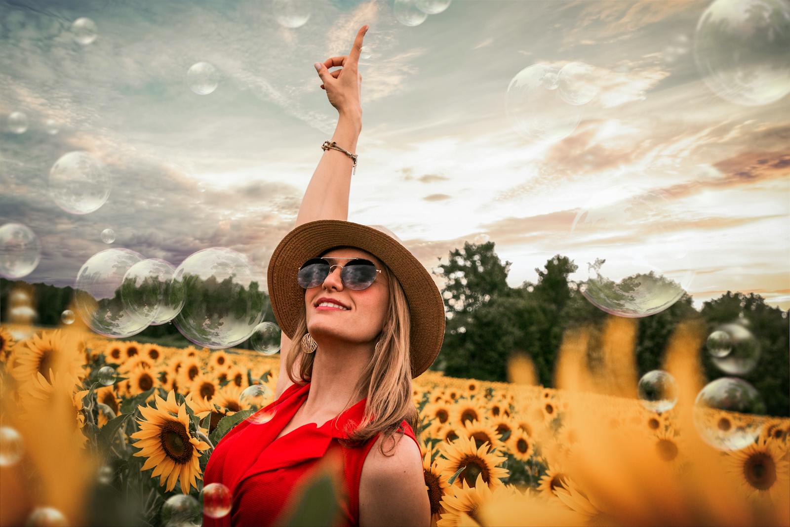 Cheerful woman enjoying a sunny day in a vibrant sunflower field while bubbles float around.