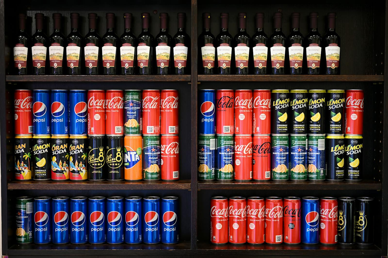 Colorful display of assorted soft drinks and wines on store shelves in Rome.