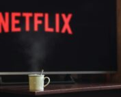 A steaming mug on a table in front of a TV displaying Netflix, creating a cozy indoor atmosphere.