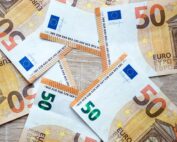 Top-down view of scattered 50 euro banknotes on a wooden surface, showcasing currency details.