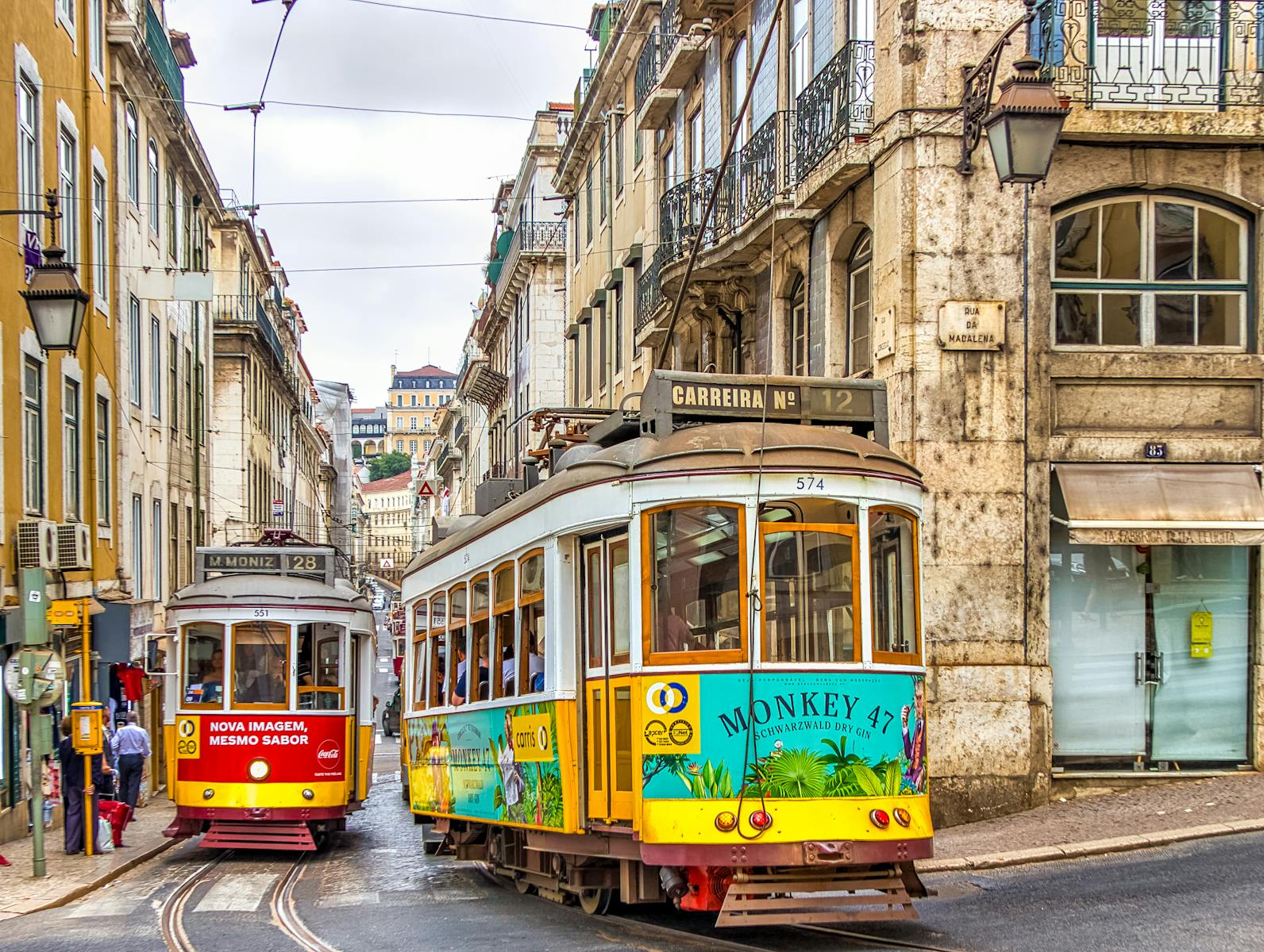 Colorful trams on a vibrant street in Lisbon, showcasing historic architecture and urban life.