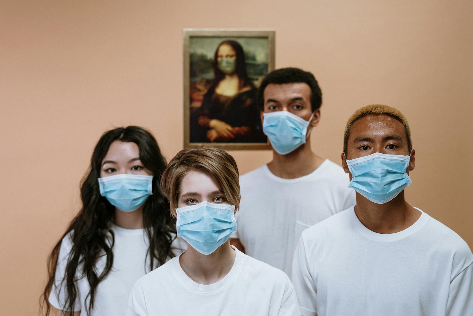 A diverse group wearing masks stands in front of a masked Mona Lisa painting.