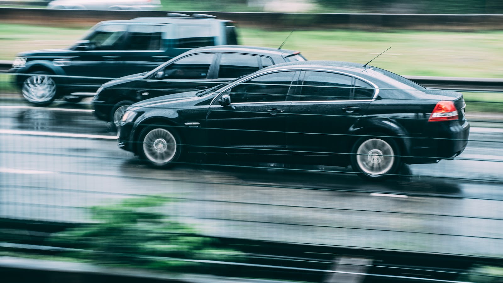 Blurred image of two cars racing on a wet highway, highlighting speed and motion.
