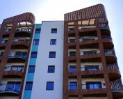 Explore the contemporary design and architecture of urban apartments with wooden accents and blue sky backdrop.