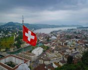 A stunning aerial view of Lucerne, Switzerland with a Swiss flag and scenic lake backdrop.