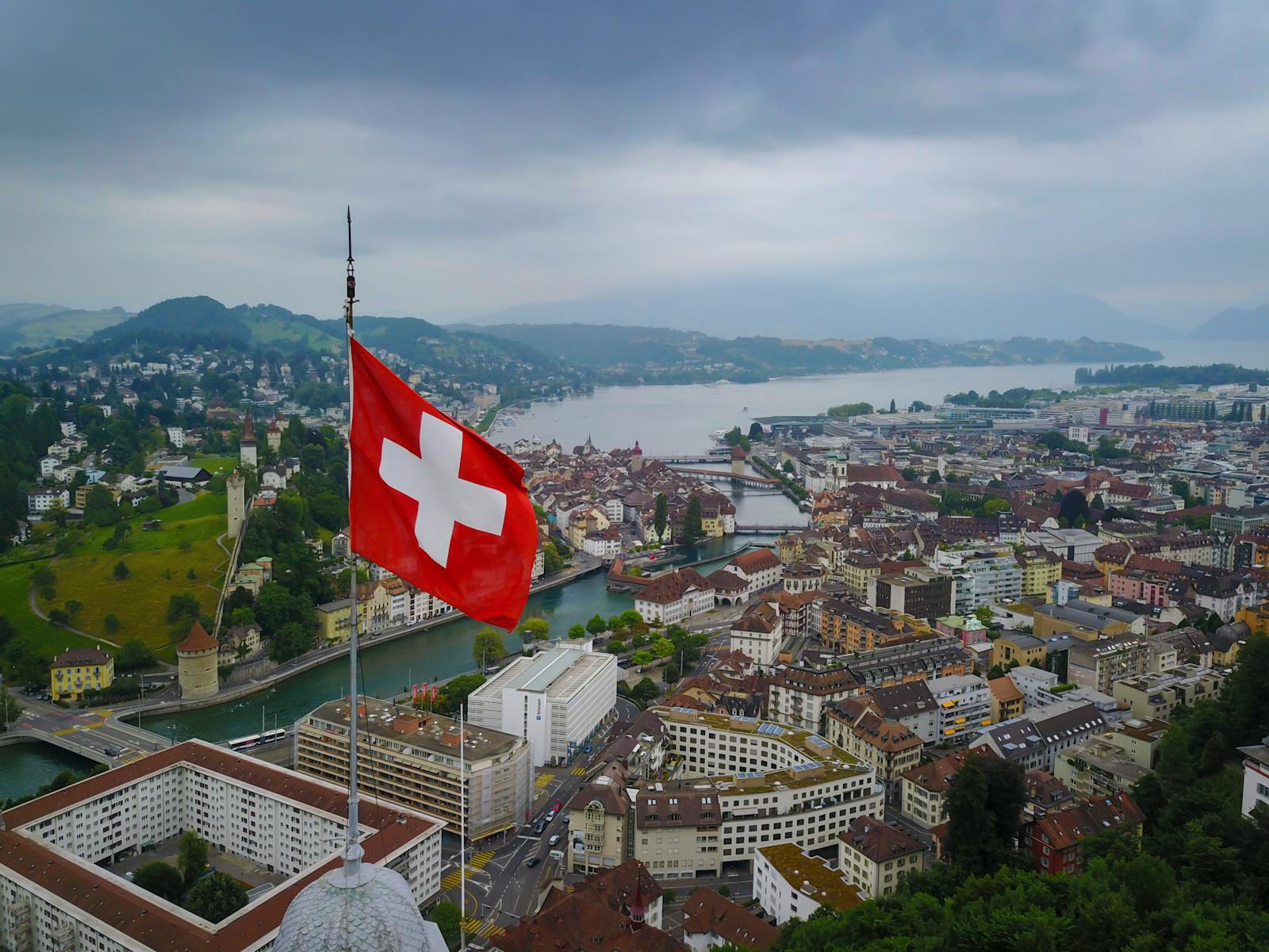 A stunning aerial view of Lucerne, Switzerland with a Swiss flag and scenic lake backdrop.