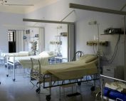Spacious hospital room with several empty beds and medical equipment, emphasizing healthcare and hygiene.