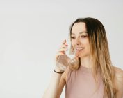 Young woman happily drinking a glass of water for healthy hydration.