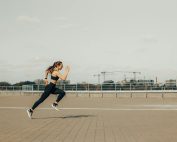 Woman sprinting on a rooftop in athletic wear during the day.