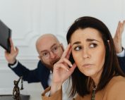 Two colleagues in a tense office situation, expressing frustration and concern.