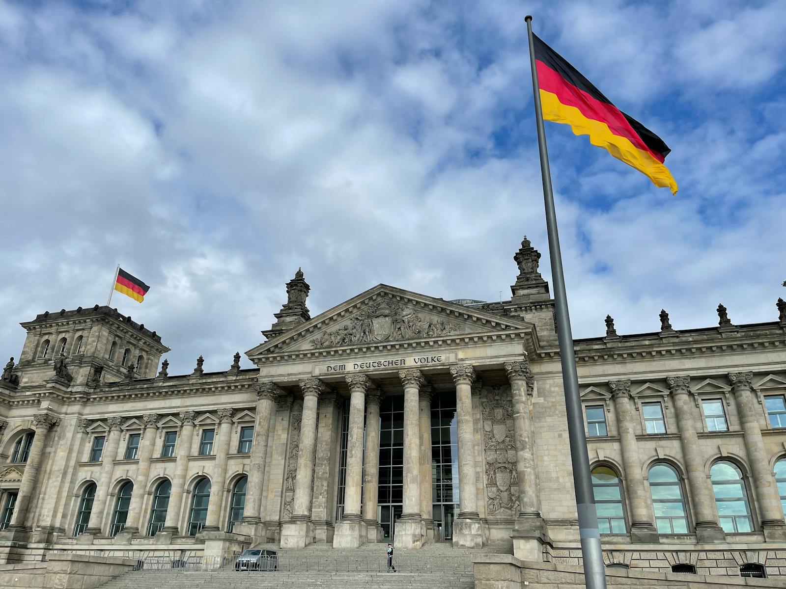 The iconic Reichstag building in Berlin with a German flag against a blue sky, symbolizing democracy.