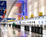 Wide view of Chicago airport terminal showcasing architecture and check-in counters. Flags and signages add vibrant detail.