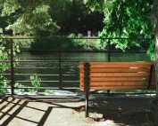 Tranquil riverside bench in Berlin's lush park setting, perfect for relaxing outdoors.