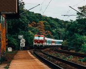 A train moves along railway tracks amidst a vibrant forest landscape near Bratislava, Slovakia.