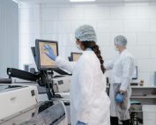 Two scientists in protective gear working with lab equipment in a high-tech laboratory.