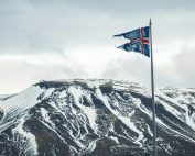 Icelandic flag flying against a backdrop of snow-covered mountains, capturing Iceland's natural beauty.