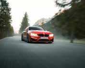 High-speed red sports car driving through scenic mountain road with blurred background