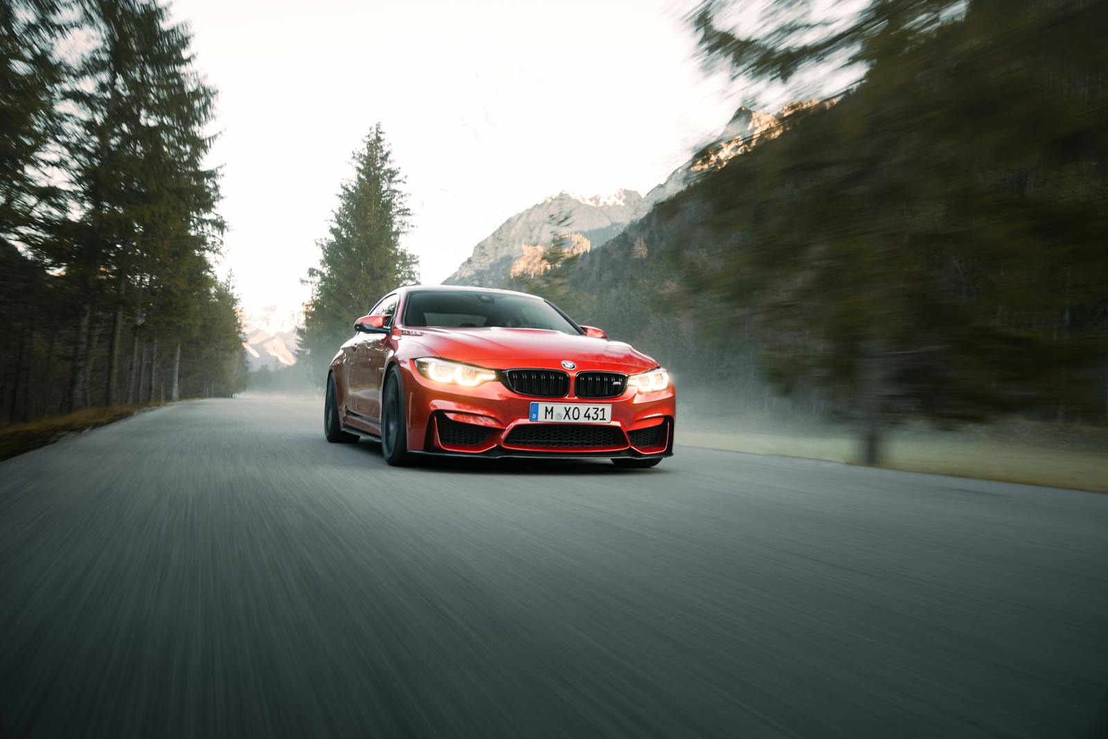 High-speed red sports car driving through scenic mountain road with blurred background