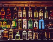 An array of various liquor bottles beautifully displayed on a bar shelf.