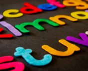 Bright and colorful felt alphabet letters arranged on a dark surface, perfect for educational and creative projects.
