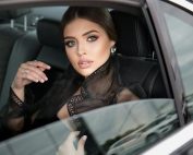 Elegant woman with striking features sitting inside a luxury car, exuding sophistication and style.