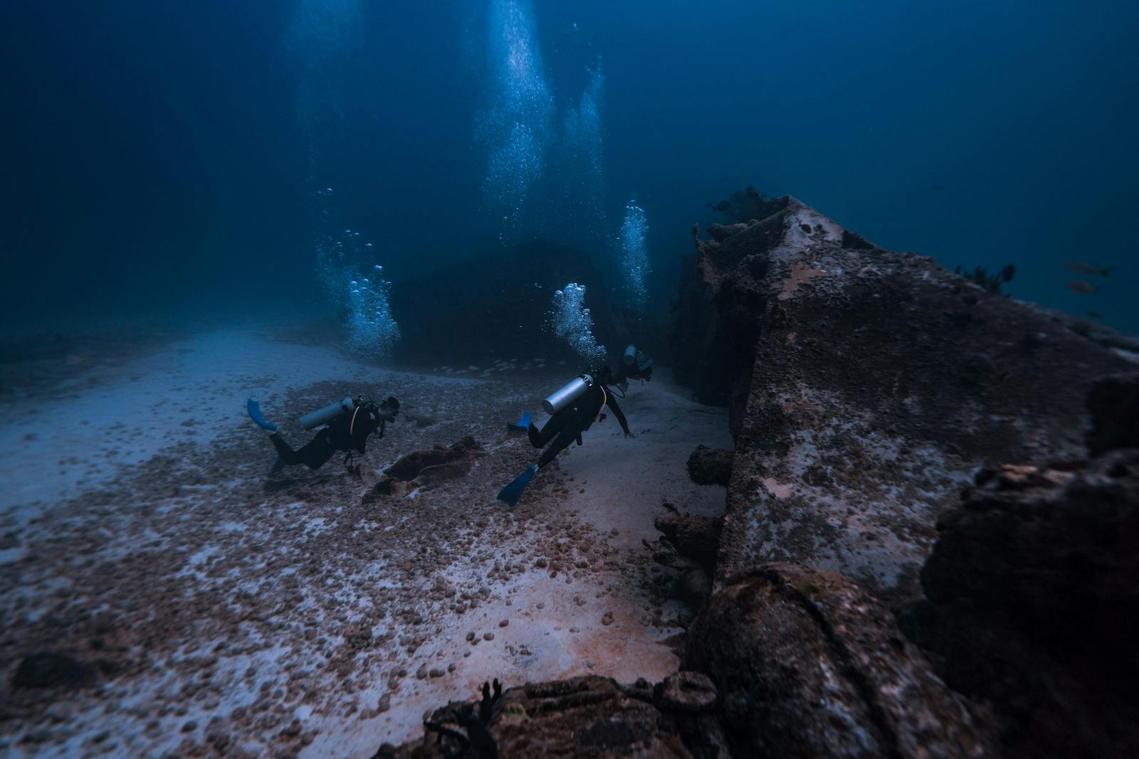 Two scuba divers exploring a shipwreck in the deep ocean waters of Isla Mujeres, Mexico.