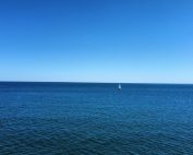 A solitary sailboat navigates the endless blue sea near Frontignan, France.