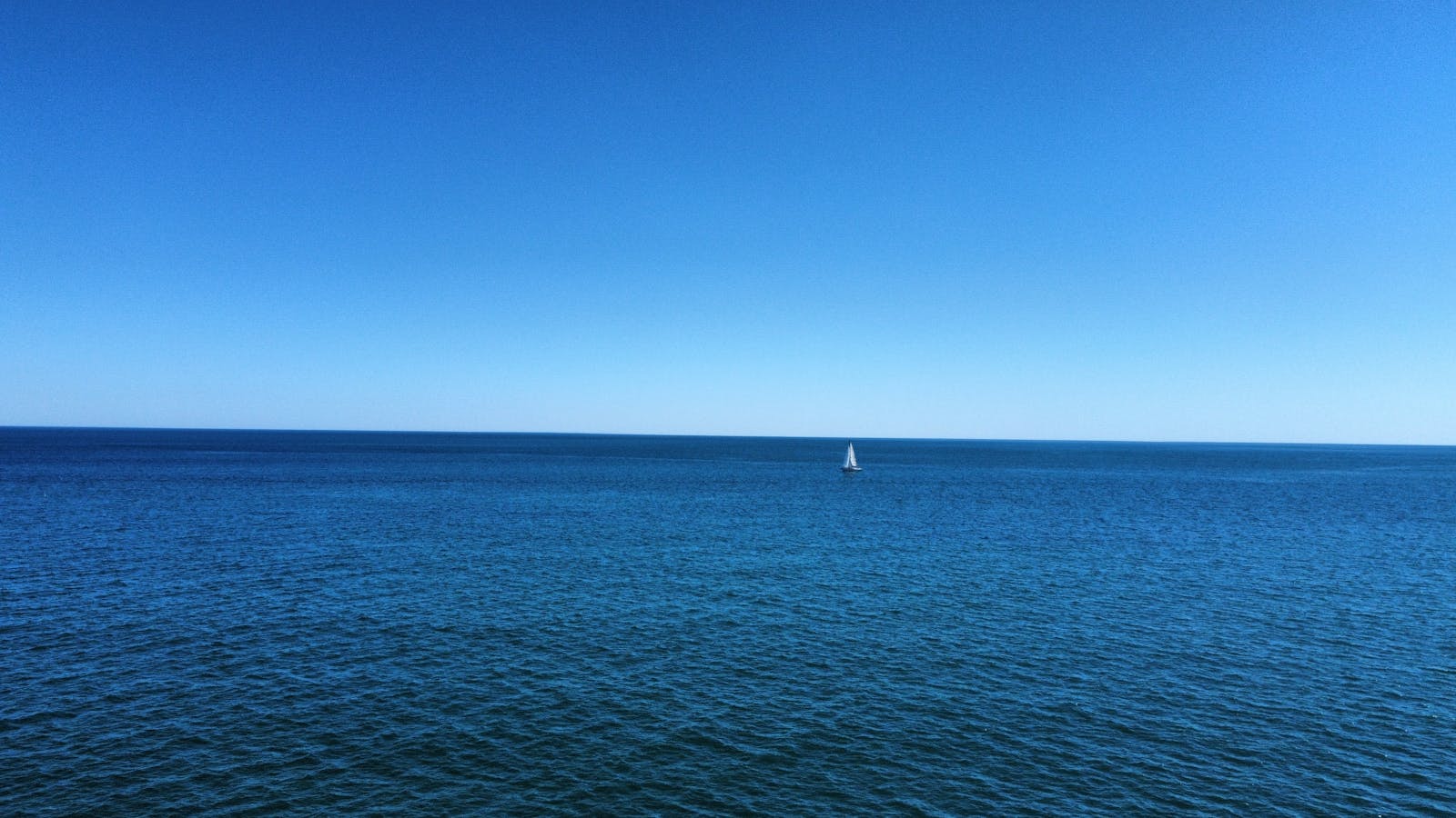 A solitary sailboat navigates the endless blue sea near Frontignan, France.