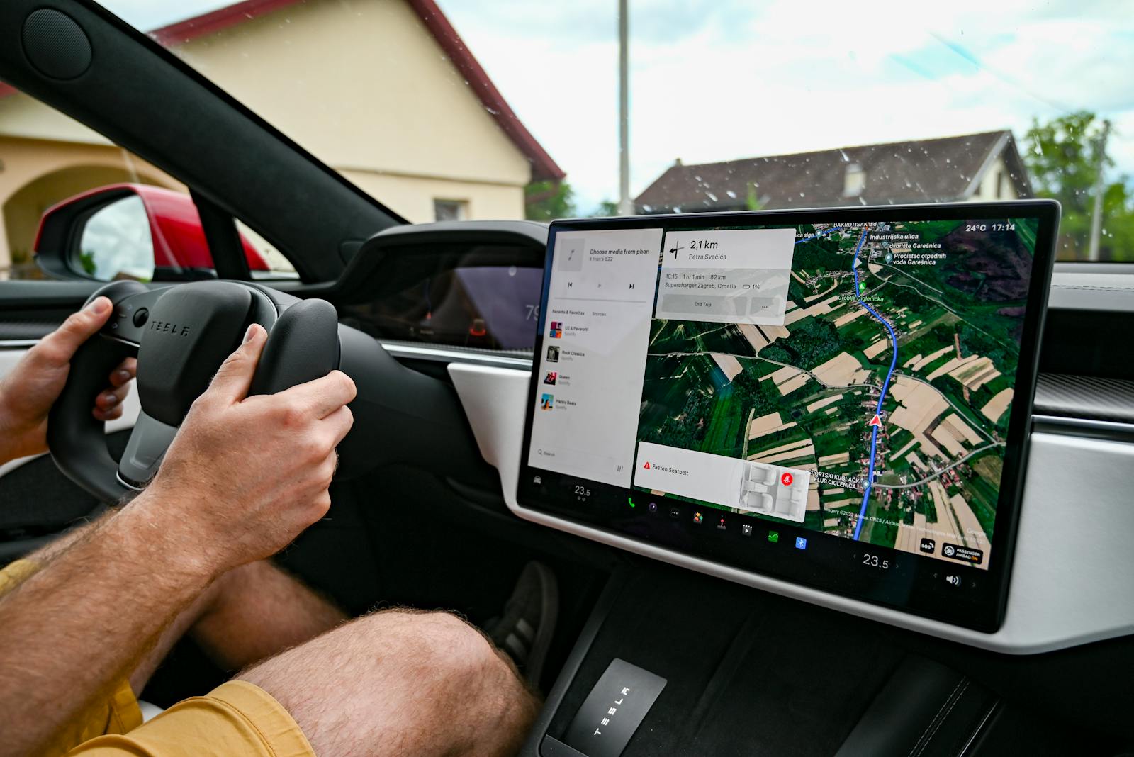 Man driving Tesla using GPS on touchscreen dashboard for navigation.