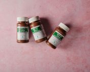 Three brown bottles of magnesium tablets on a soft pink background, ideal for health-themed content.