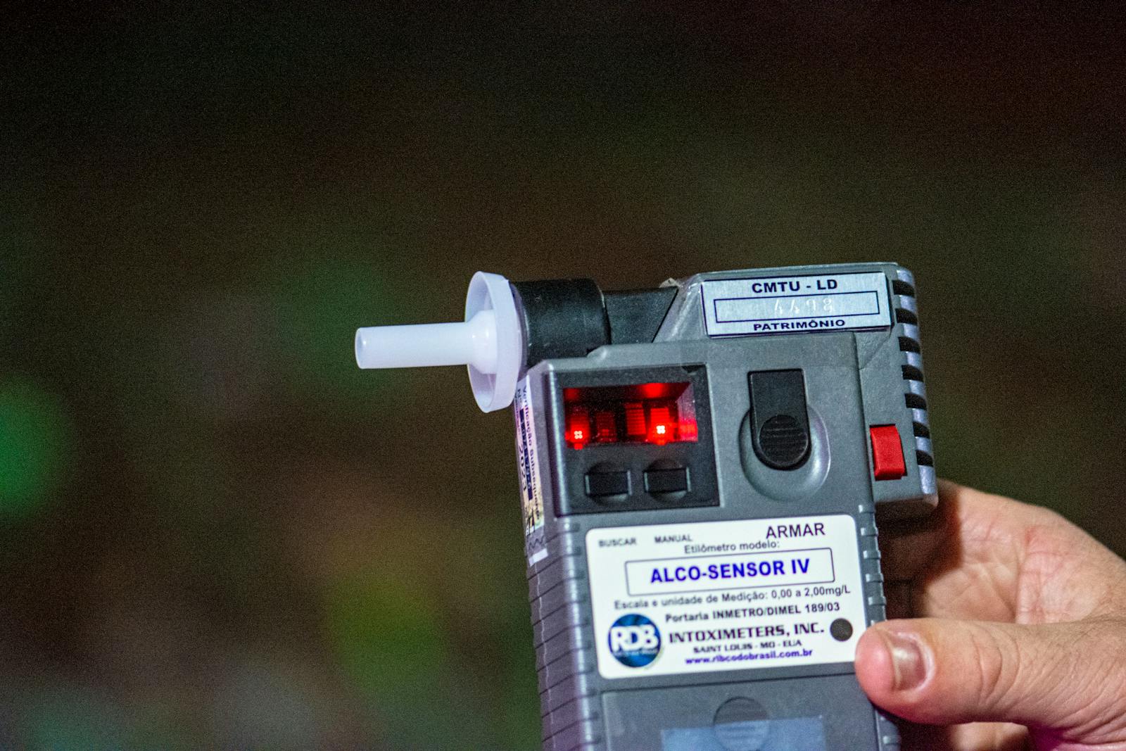 Detailed close-up of Alco-Sensor IV breathalyzer device held by a person outdoors in Londrina, Brazil.