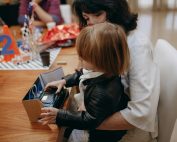 A mother and child opening a gift during a birthday party, featuring a toy car.