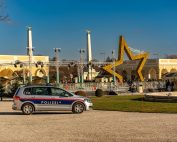 A police car parked near a large star decoration at a Christmas market in Vienna, Austria.
