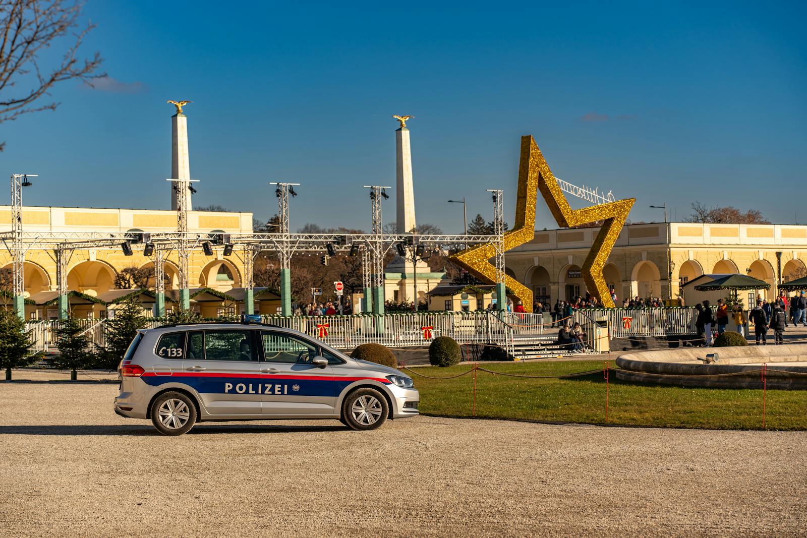 A police car parked near a large star decoration at a Christmas market in Vienna, Austria.