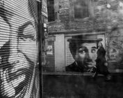 Black and white street art scene capturing a woman walking by iconic mural in İstanbul.