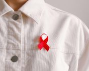 Red ribbon for HIV/AIDS awareness pinned on a white shirt symbolizing support and solidarity.