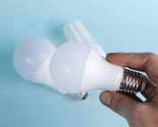 Close-up of hand holding energy-efficient LED light bulbs on a blue background.
