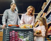 A joyful family of three shopping together in a supermarket, creating a memorable experience.