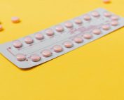 A blister pack of pink pills placed on a vibrant yellow background, symbolizing medicine and healthcare.