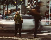 Blurred city street scene with pedestrians and vehicles in motion, showcasing urban hustle and bustle.