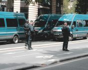 Police officers standing in front of Gendarmerie vans during a city patrol, showcasing urban security activities.