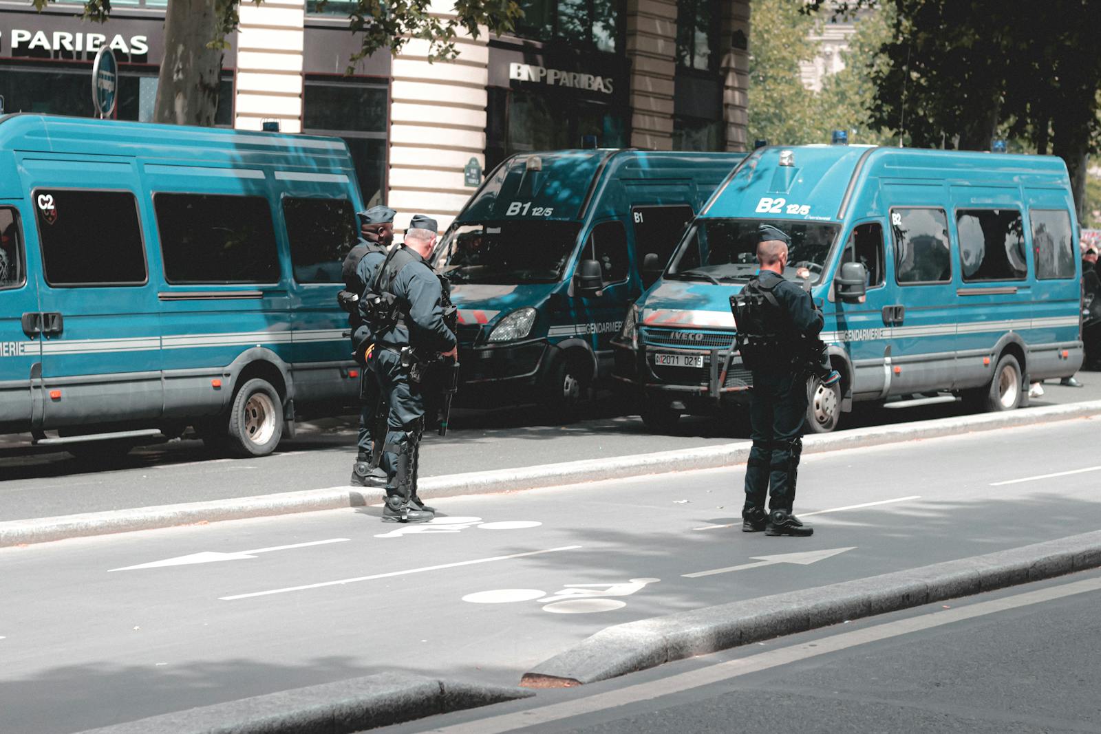 Police officers standing in front of Gendarmerie vans during a city patrol, showcasing urban security activities.