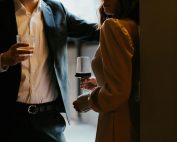 A stylishly dressed couple sharing a romantic moment with drinks at an upscale venue.