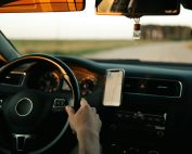 Interior of a car with GPS navigation, focusing on the driver and dashboard during the day.