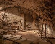 An atmospheric shot of an old, abandoned basement with weathered stone walls and scattered debris.